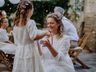 Little girl giving wedding gift to mature bride at wedding backyard party.